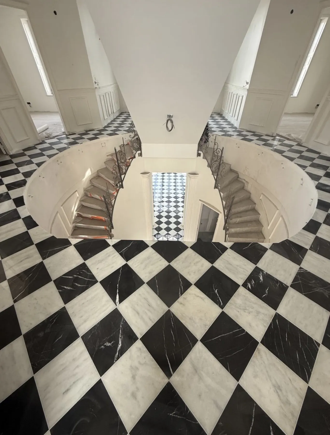 Hall en damier de marbre noir et blanc, autour d'un escalier hélicoïdal